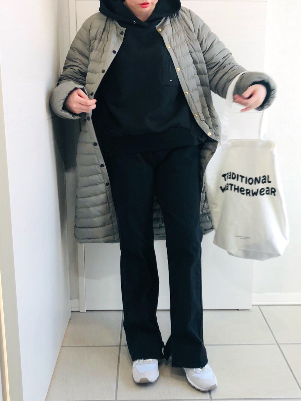 グレー系のダウンジャケット/コート、ブラック系のパーカー、ブラック系のデニムパンツを着用したレディースの冬コーディネートの2枚目の写真