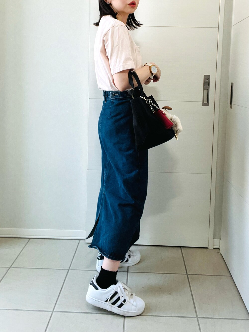 ピンク系のTシャツ/カットソー、ブルー系のデニムスカート、ホワイト系のスニーカーを着用したレディースの夏コーディネートの5枚目の写真