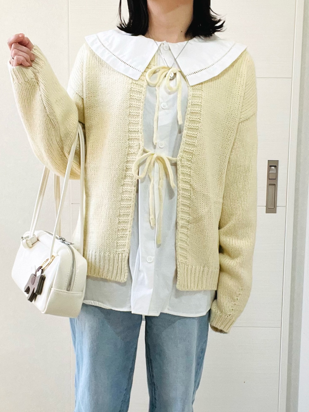 ホワイト系のカーディガン/ボレロ、ホワイト系のシャツ/ブラウス、ブルー系のデニムパンツを着用したレディースの冬コーディネートの2枚目の写真