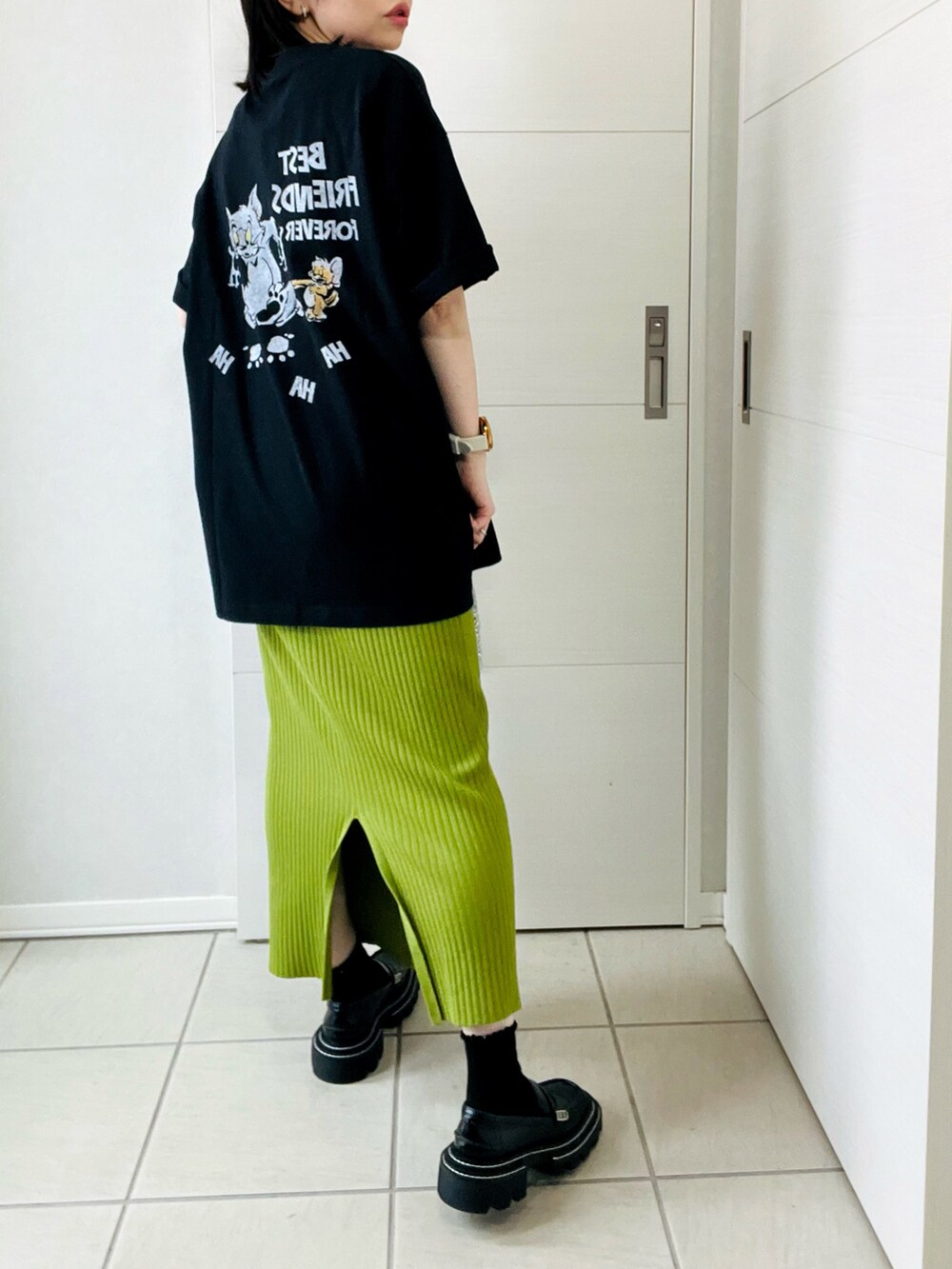 ブラック系のTシャツ/カットソー、グリーン系のスカート、ブラック系のローファーを着用したレディースの春コーディネートの3枚目の写真
