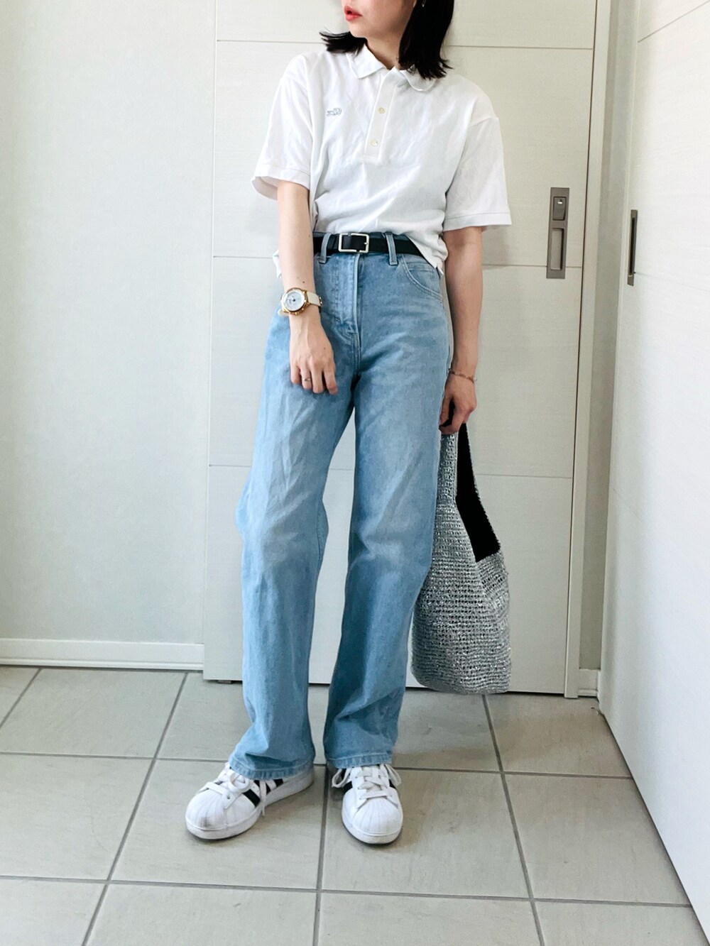 ホワイト系のポロシャツ、ブルー系のデニムパンツ、ホワイト系のスニーカーを着用したレディースの夏コーディネートの4枚目の写真