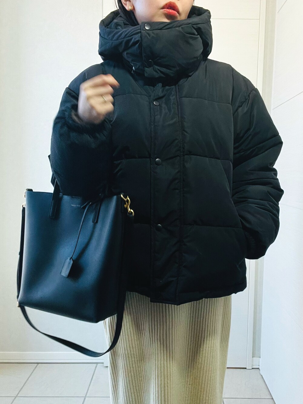 ブラック系のダウンジャケット/コート、グレー系のニット/セーター、ホワイト系のスカートを着用したレディースの冬コーディネートの3枚目の写真