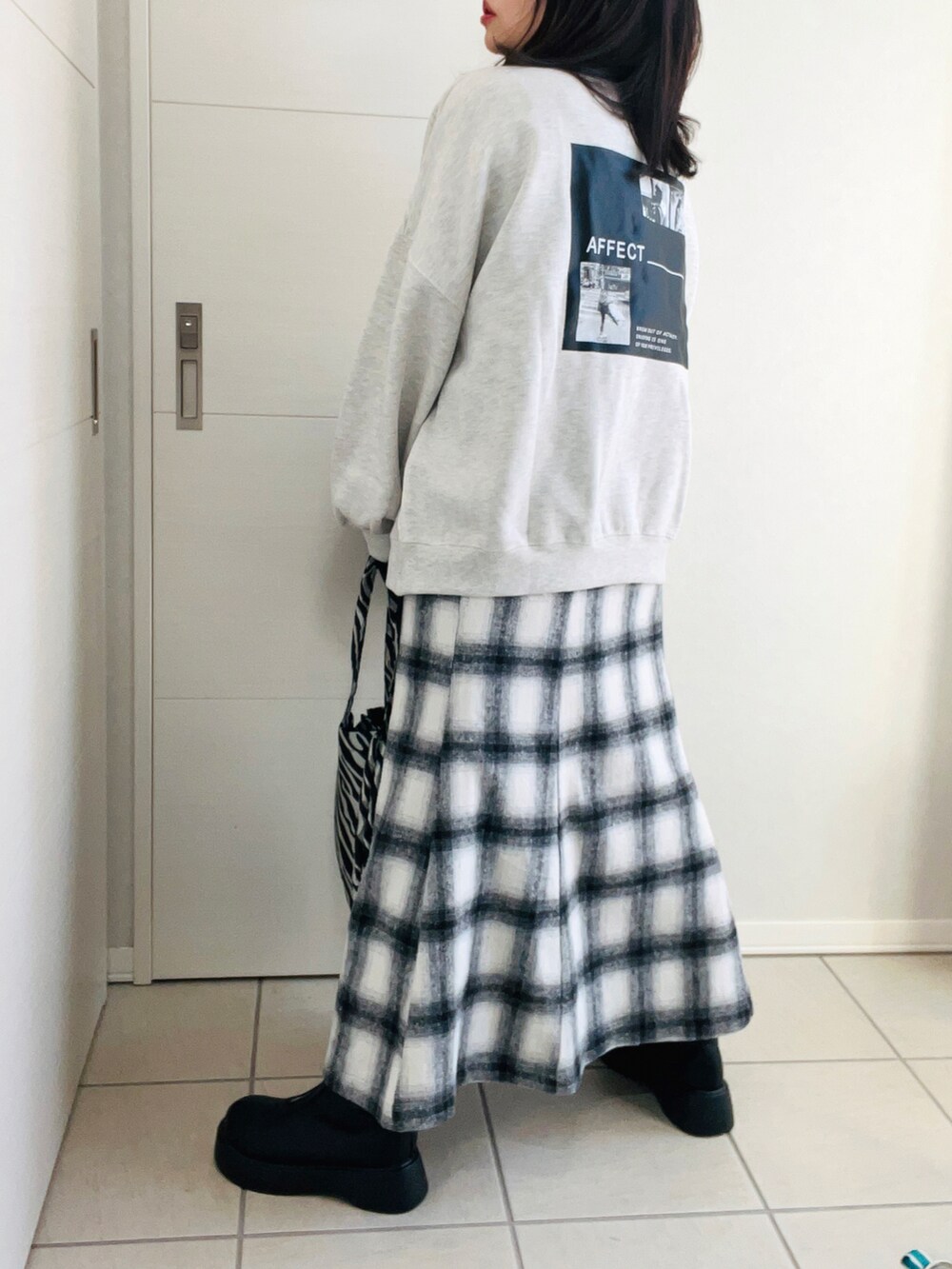 ブラック系のベスト、グレー系のスウェット、ホワイト系のスカートを着用したレディースの冬コーディネートの3枚目の写真