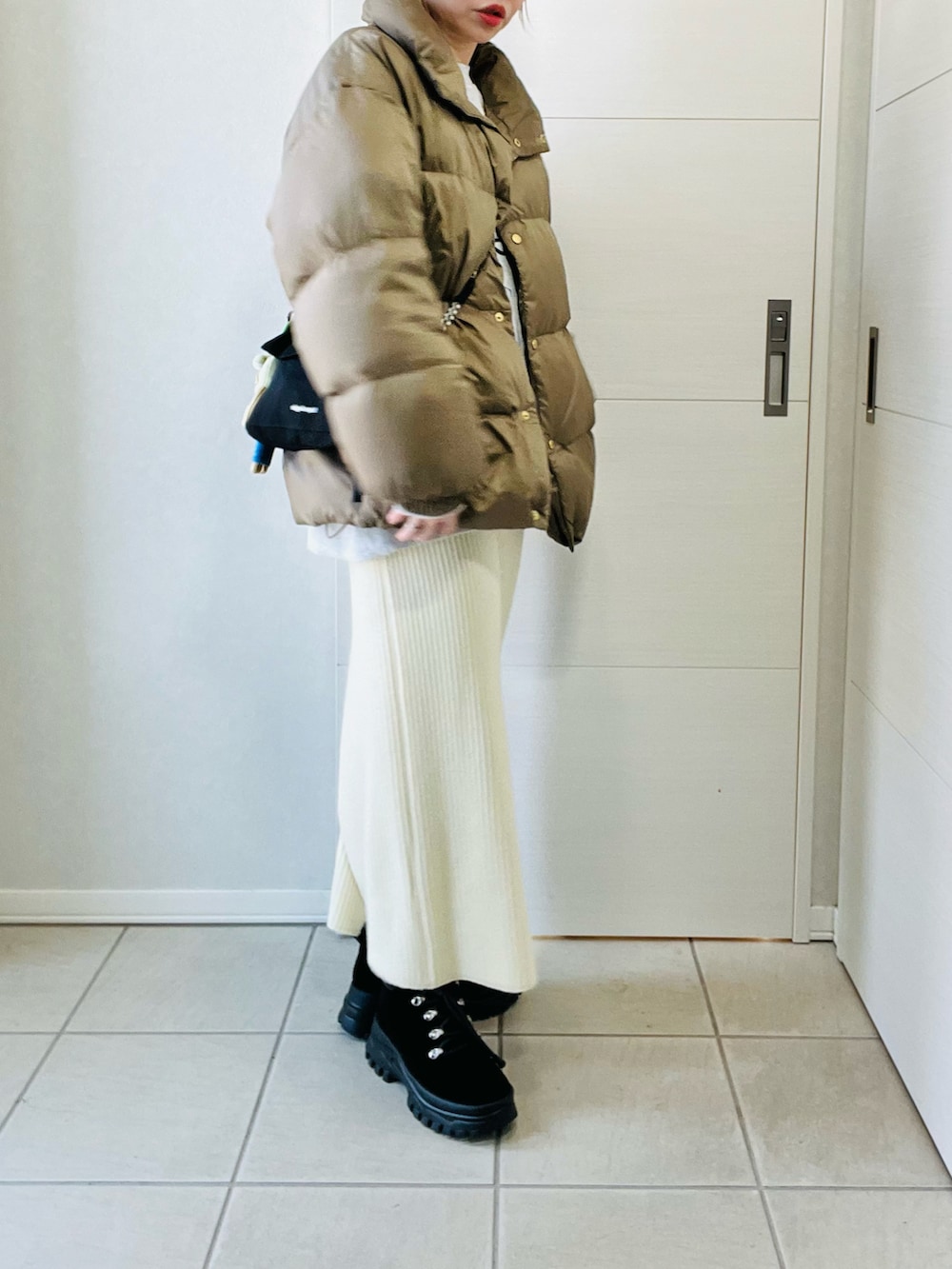 ベージュ系のダウンジャケット/コート、ホワイト系のスカート、ブラック系のブーツを着用したレディースの冬コーディネートの3枚目の写真