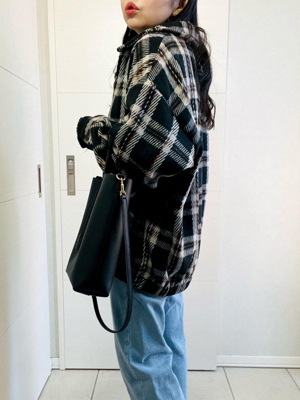 ブラック系のブルゾン、ブラック系のニット/セーター、ブルー系のデニムパンツを着用したレディースの冬コーディネートの3枚目の写真