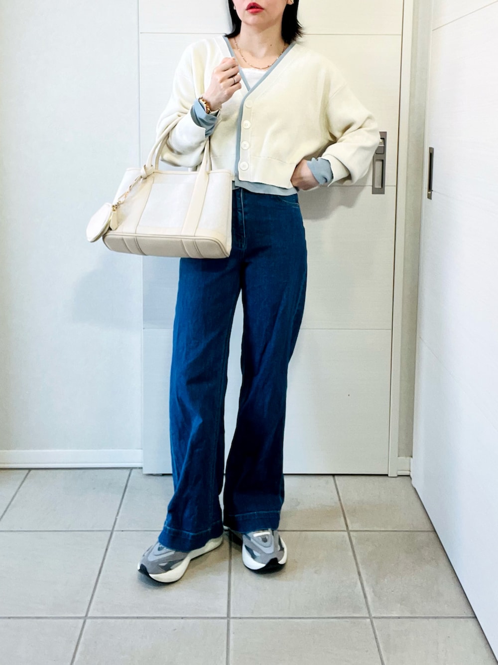 ホワイト系のカーディガン/ボレロ、グレー系のスニーカー、ブルー系のデニムパンツを着用したレディースの春コーディネートの4枚目の写真