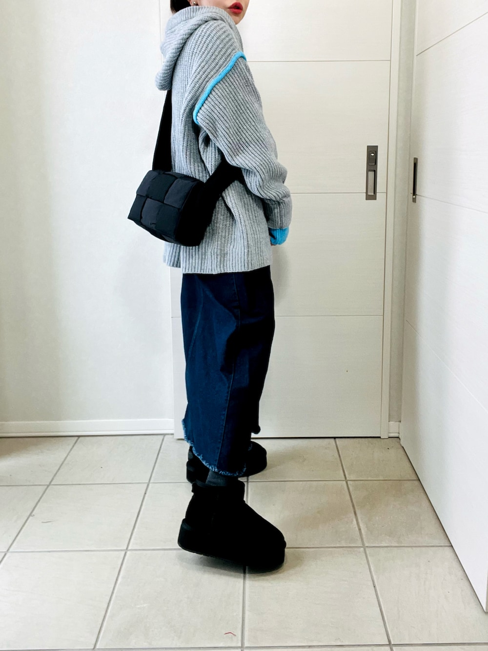 グレー系のニット/セーター、ブルー系のスカート、ブラック系のブーツを着用したレディースの冬コーディネートの5枚目の写真