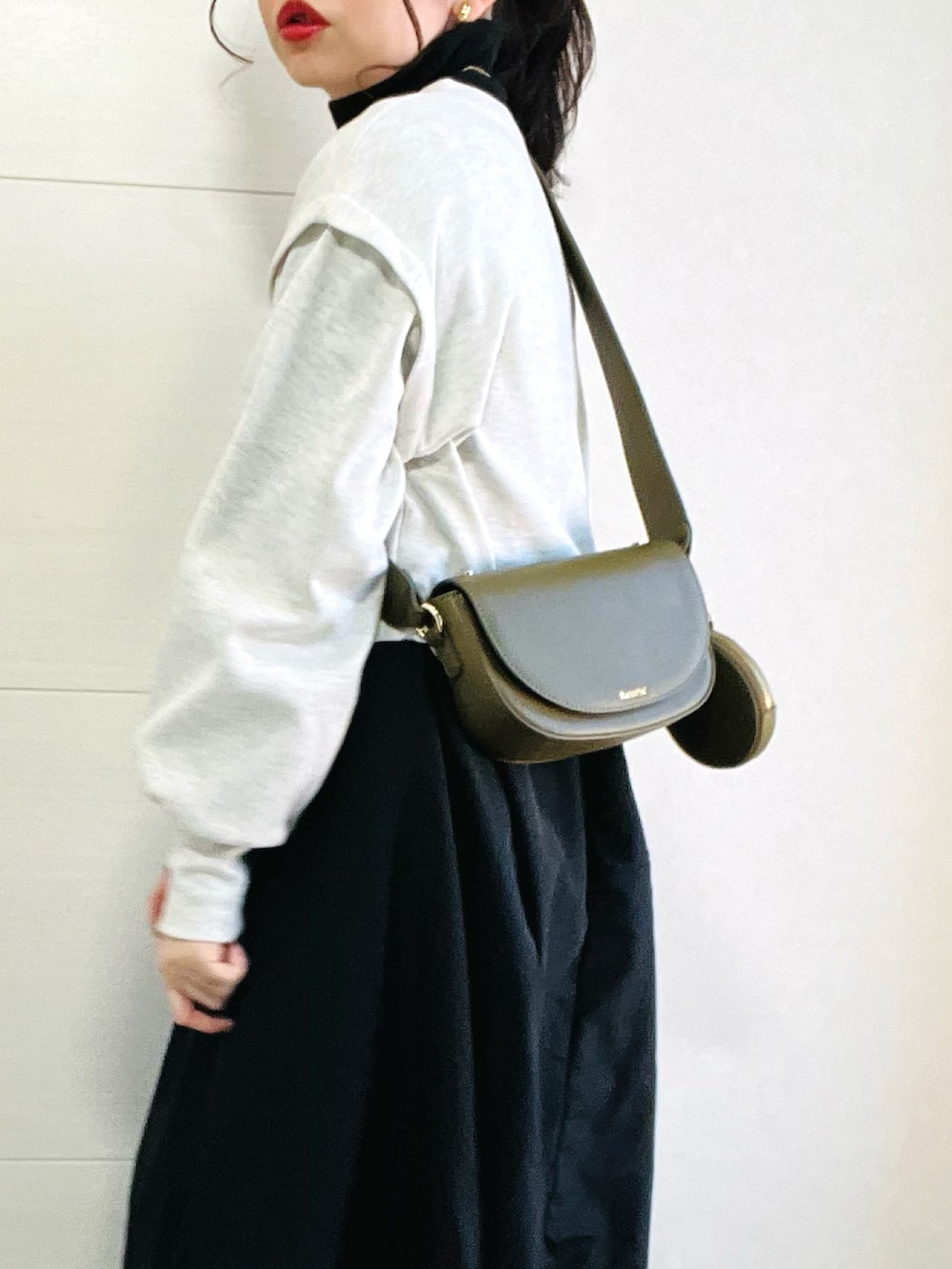 グレー系のワンピース、グリーン系のショルダーバッグ、ブラック系のスニーカーを着用したレディースの冬コーディネートの3枚目の写真
