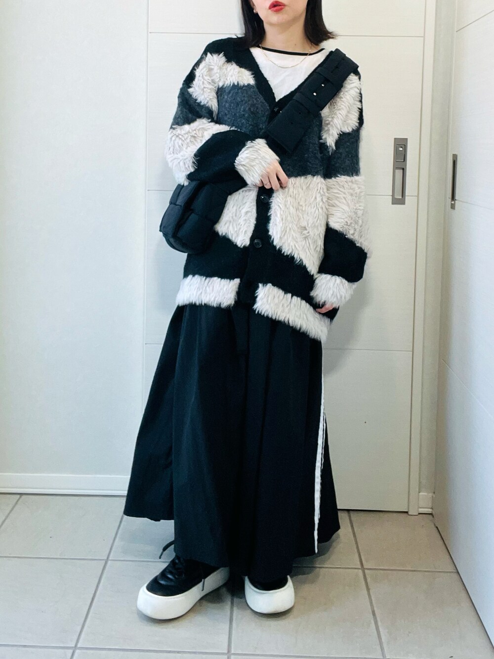 ブラック系のカーディガン/ボレロ、ブラック系のスニーカー、ブラック系のスカートを着用したレディースの秋コーディネートの4枚目の写真