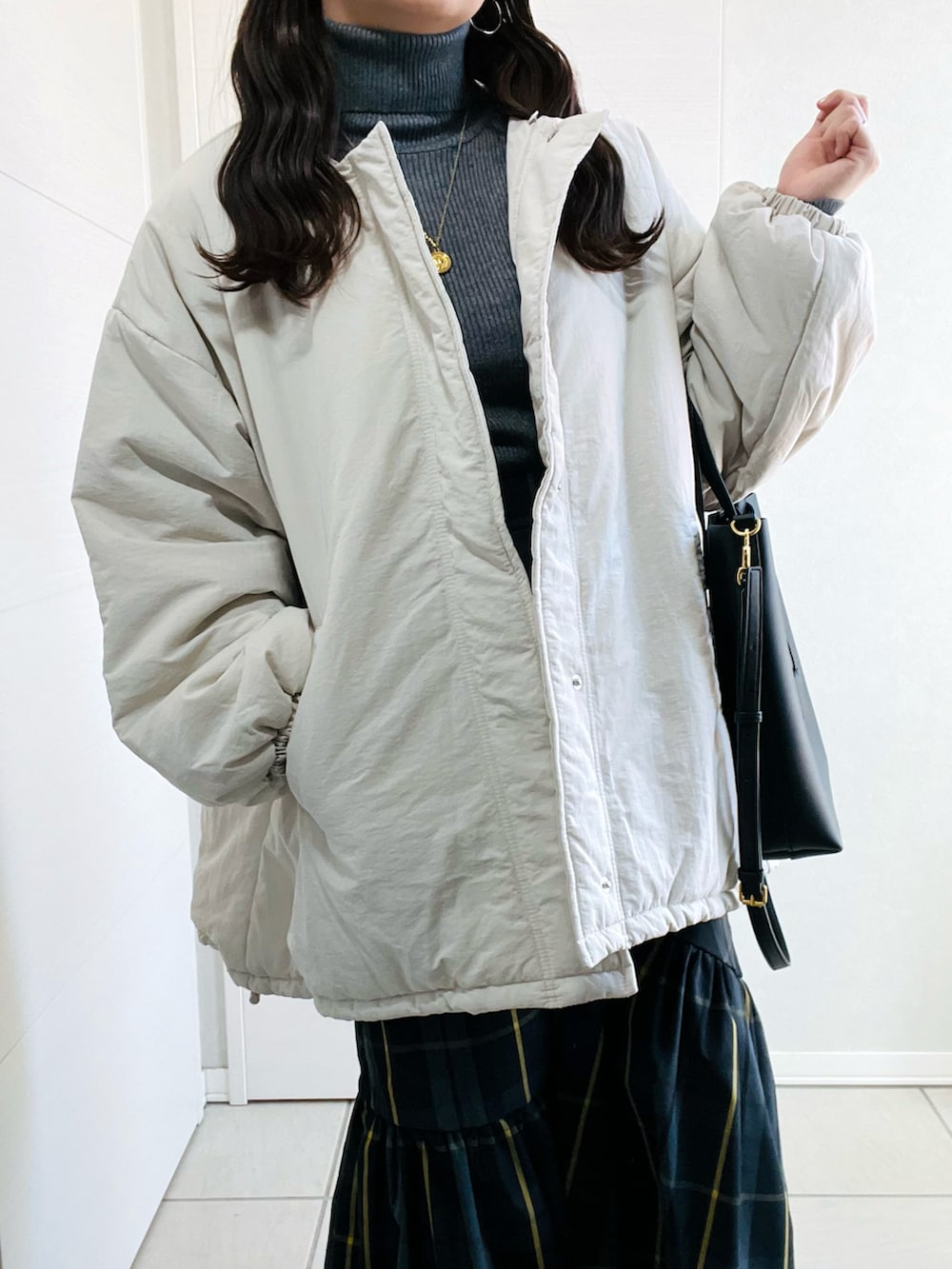 ホワイト系のブルゾン、グレー系のニット/セーター、ブラック系のスカートを着用したレディースの秋コーディネートの4枚目の写真