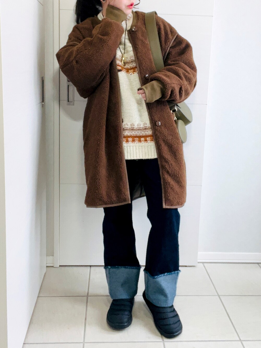 ブラウン系のニット/セーター、ブラウン系のその他アウター、ブルー系のデニムパンツを着用したレディースの冬コーディネートの5枚目の写真