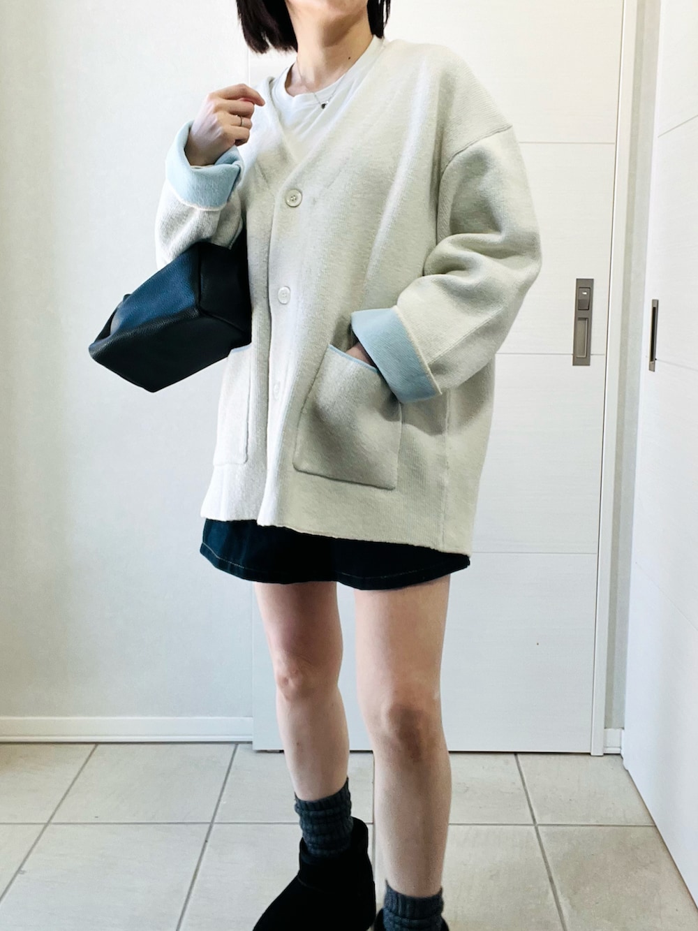 ホワイト系のカーディガン/ボレロ、ブラック系のブーツ、ブラック系のその他パンツを着用したレディースの冬コーディネートの2枚目の写真