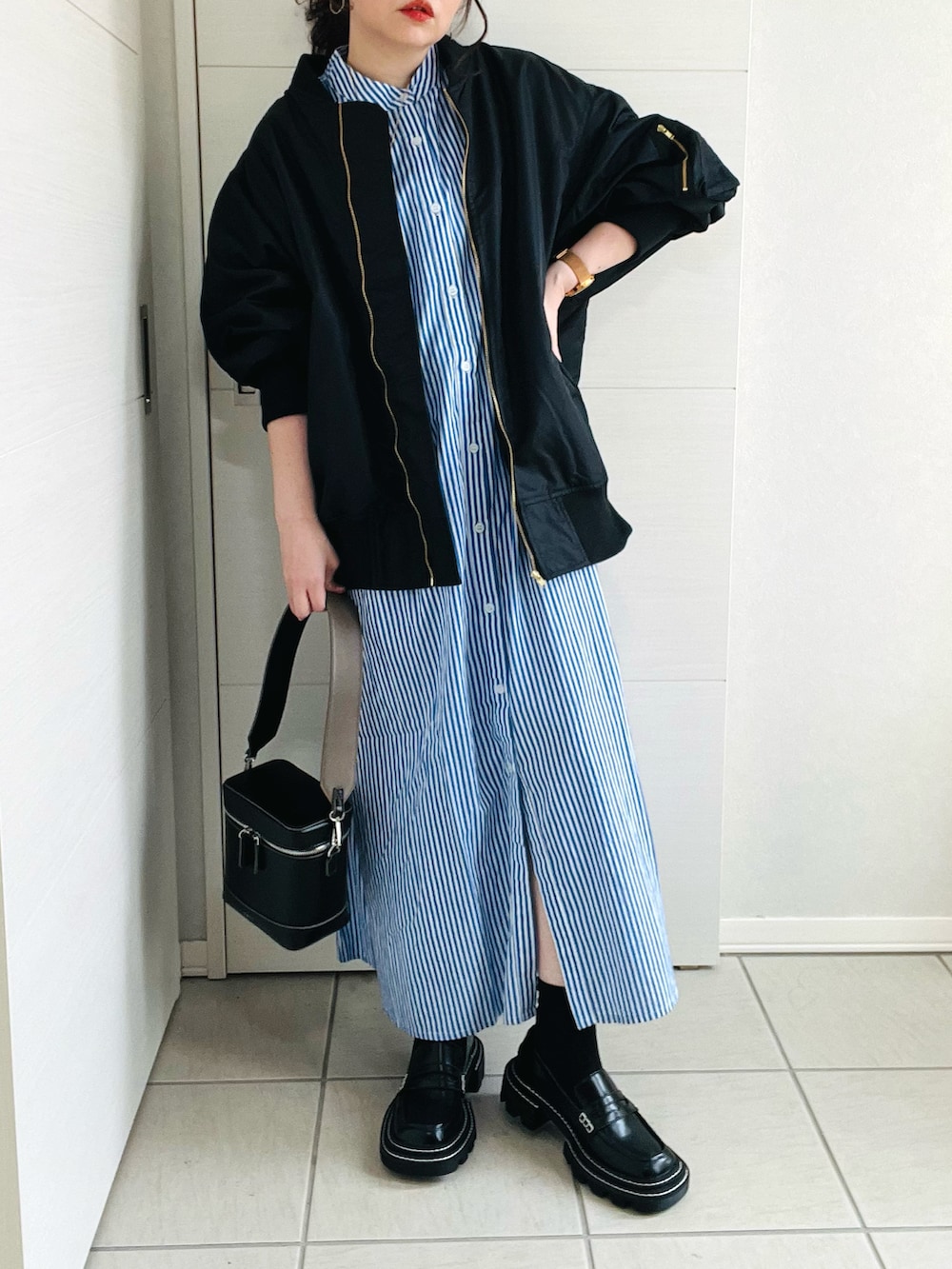 ブルー系のシャツワンピース、ブラック系のブルゾン、ブラック系のローファーを着用したレディースの春コーディネートの2枚目の写真