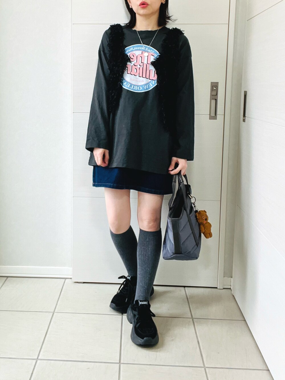 ブラック系のベスト、グレー系のTシャツ/カットソー、ブルー系のデニムスカートを着用したレディースの春コーディネートの3枚目の写真