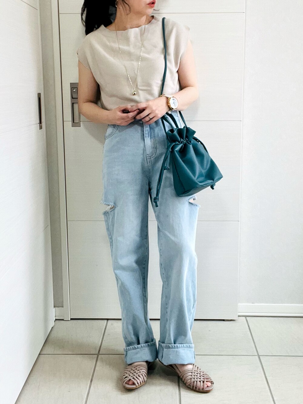 ベージュ系のニット/セーター、ブルー系のデニムパンツ、グレー系のサンダルを着用したレディースの夏コーディネートの2枚目の写真