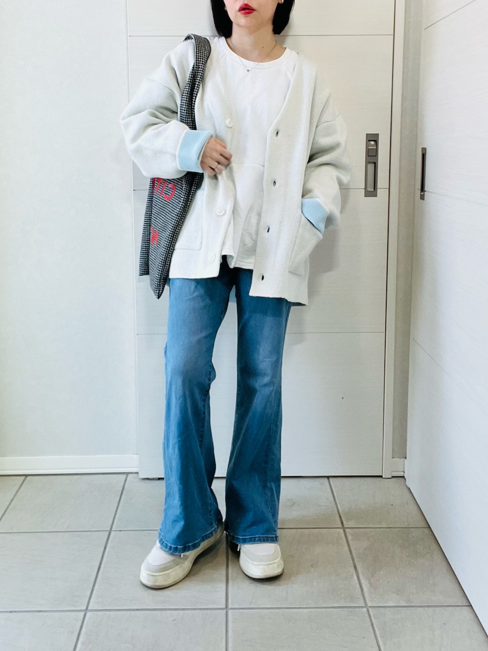 ホワイト系のカーディガン/ボレロ、ブルー系のデニムパンツ、ブラック系のトートバッグを着用したレディースの春コーディネートの4枚目の写真