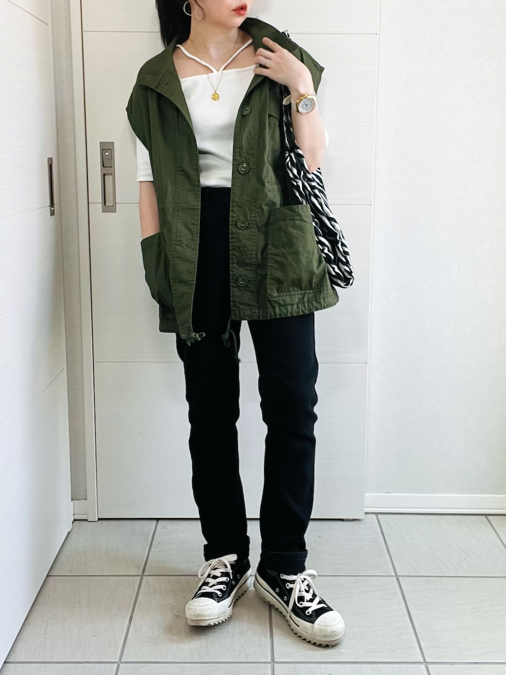 ホワイト系のTシャツ/カットソー、グリーン系のベスト、ブラック系のデニムパンツを着用したレディースの春コーディネートの2枚目の写真