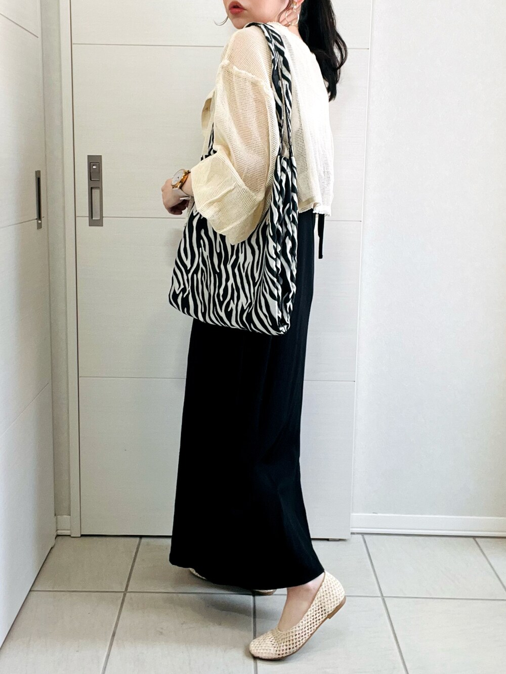 ホワイト系のカーディガン/ボレロ、ブラック系のワンピース、ベージュ系のパンプスを着用したレディースの春コーディネートの5枚目の写真