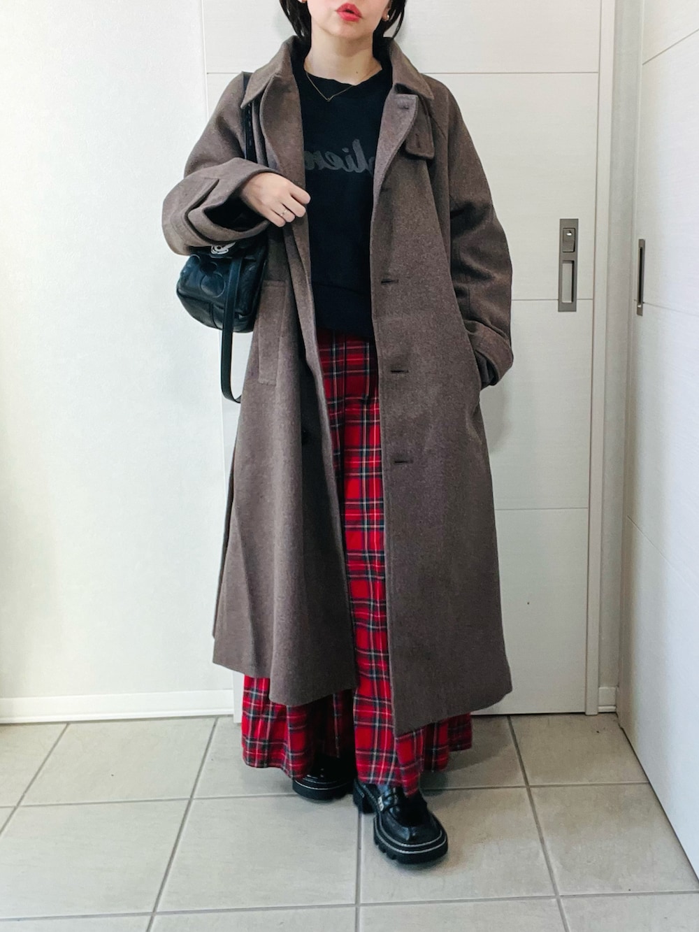 ブラウン系のステンカラーコート、ブラック系のスウェット、レッド系のスカートを着用したレディースの秋コーディネートの4枚目の写真
