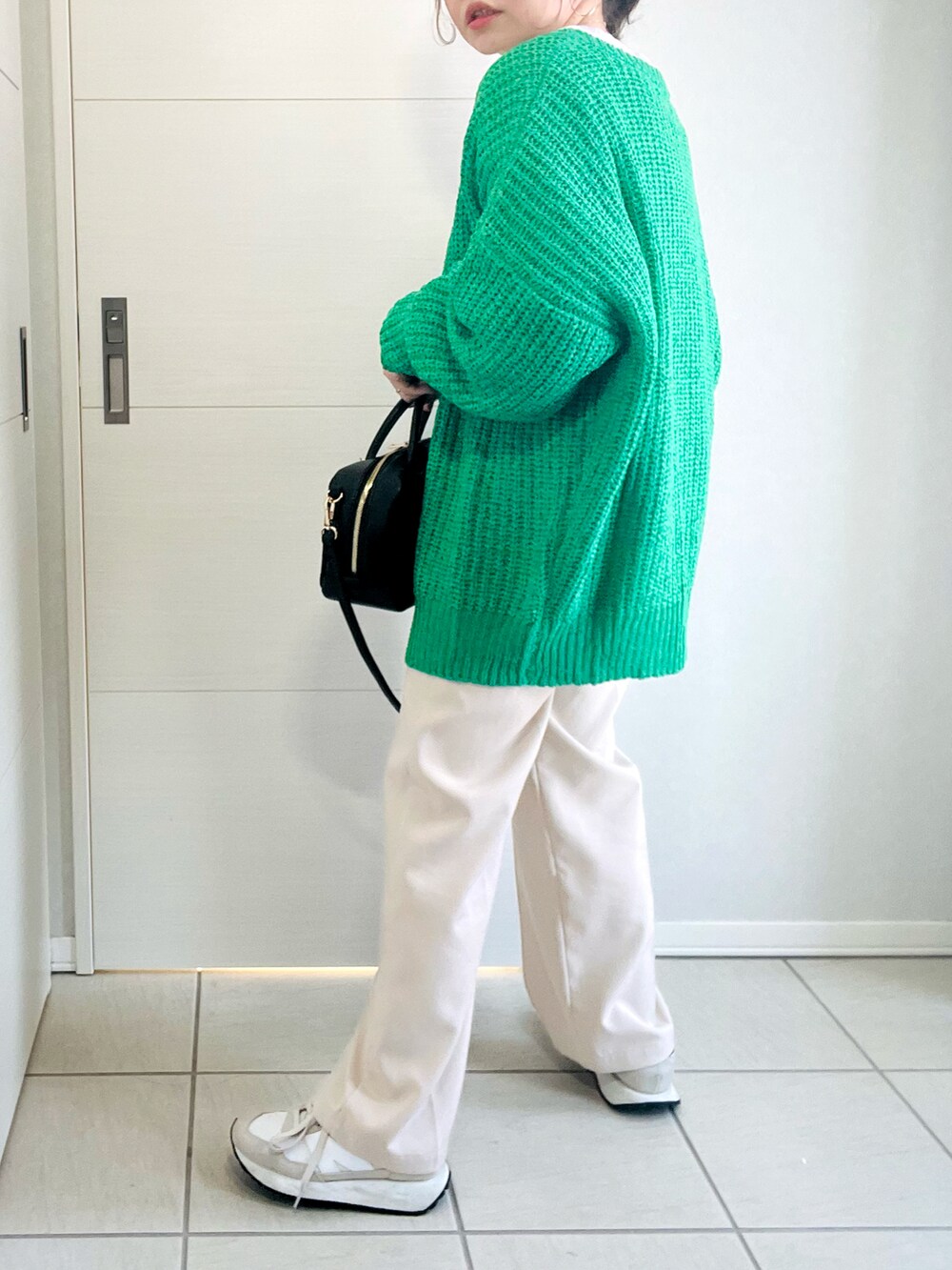 グレー系のスウェット、グリーン系のカーディガン/ボレロ、ホワイト系のスラックスを着用したレディースの春コーディネートの4枚目の写真