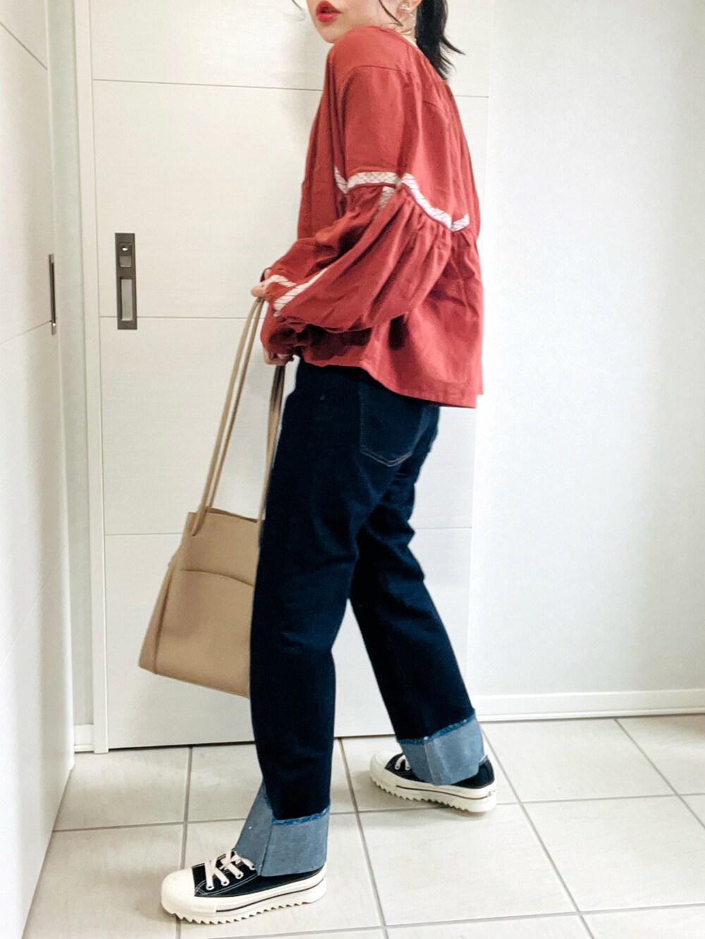 ブラウン系のシャツ/ブラウス、ブルー系のデニムパンツ、ブラック系のスニーカーを着用したレディースの秋コーディネートの4枚目の写真