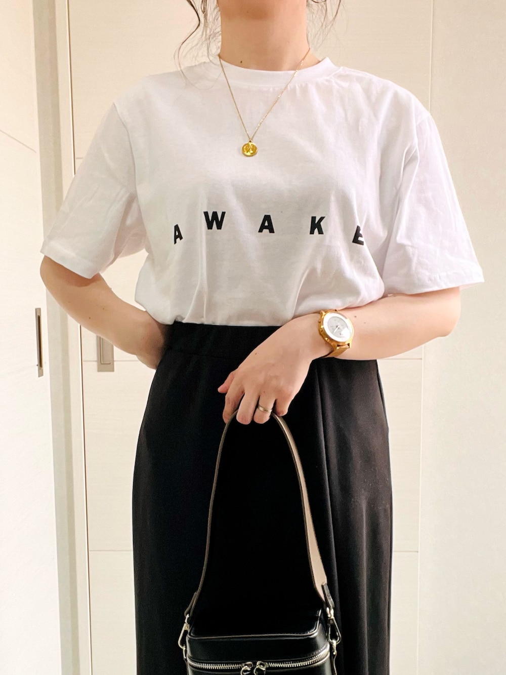 ホワイト系のTシャツ/カットソー、ブラック系のスカート、ブラック系のスニーカーを着用したレディースの春コーディネートの2枚目の写真