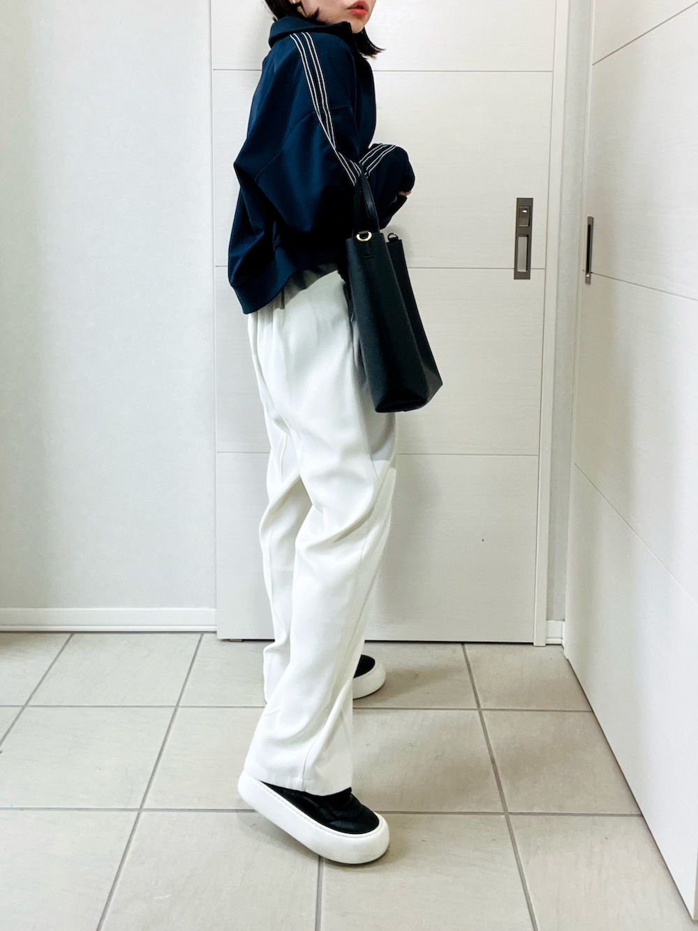 ブルー系のブルゾン、ホワイト系のスラックス、ブラック系のスニーカーを着用したレディースの秋コーディネートの5枚目の写真