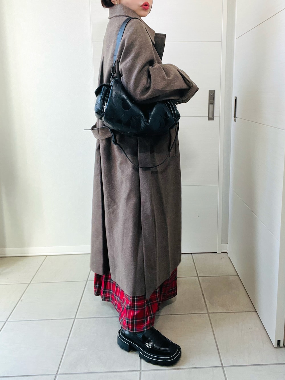 ブラウン系のステンカラーコート、ブラック系のスウェット、レッド系のスカートを着用したレディースの秋コーディネートの3枚目の写真