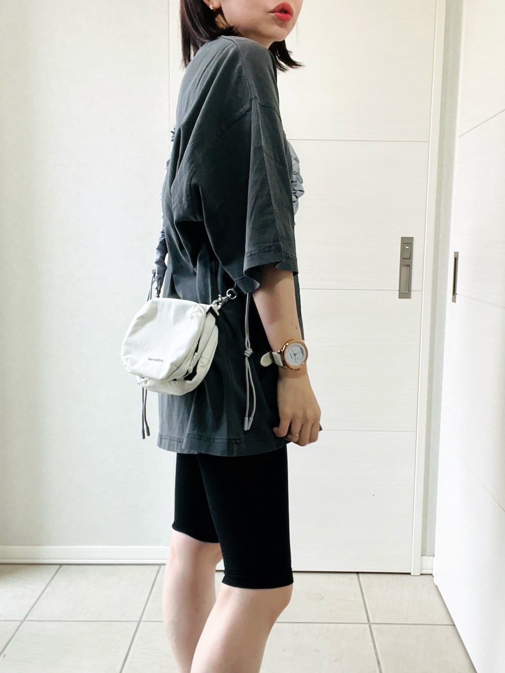 グレー系のTシャツ/カットソー、ブラック系のスニーカー、ホワイト系のショルダーバッグを着用したレディースの夏コーディネートの3枚目の写真