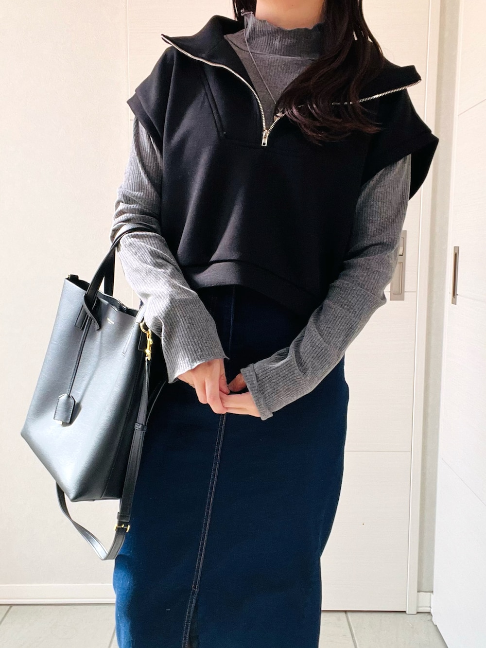 ブラック系のベスト、グレー系のTシャツ/カットソー、ブルー系のデニムスカートを着用したレディースの秋コーディネートの2枚目の写真
