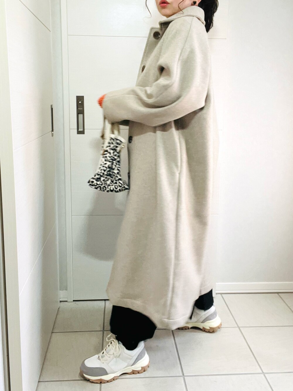 ベージュ系のステンカラーコート、ベージュ系のTシャツ/カットソー、ブラック系のワンピースを着用したレディースの秋コーディネートの4枚目の写真