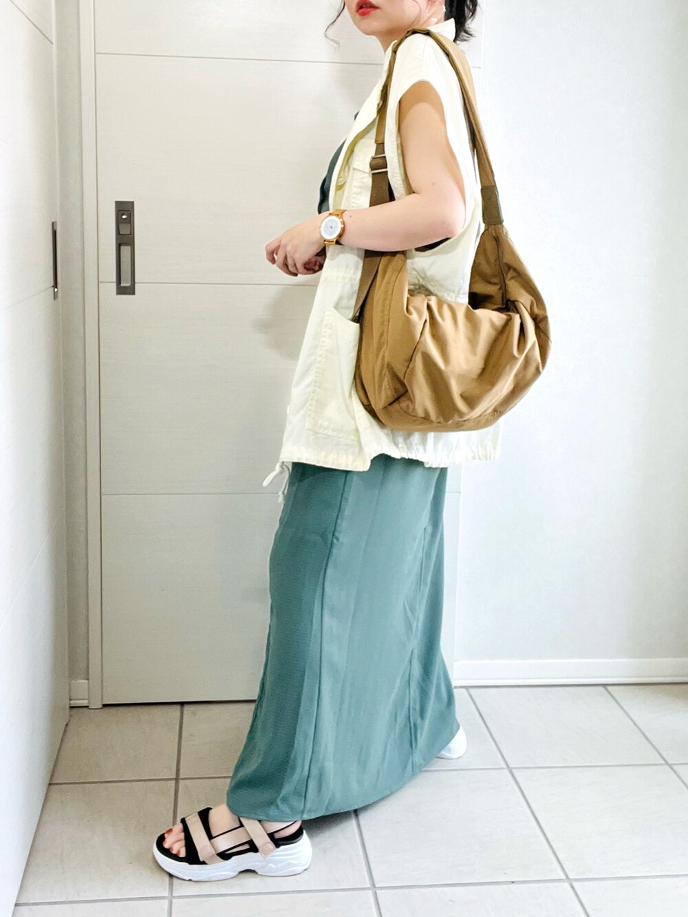 グリーン系のワンピース、ホワイト系のベスト、ベージュ系のサンダルを着用したレディースの夏コーディネートの4枚目の写真