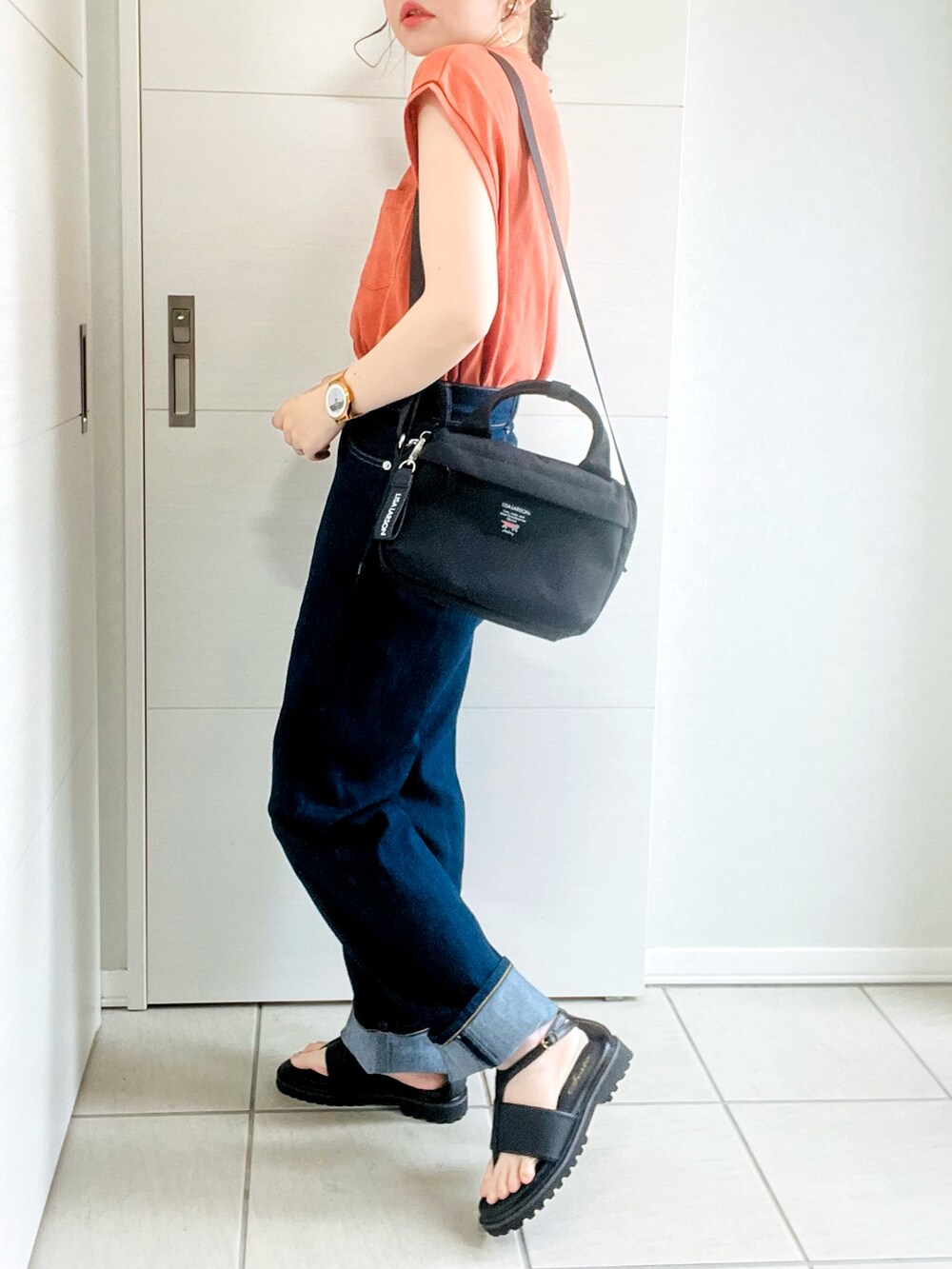 オレンジ系のTシャツ/カットソー、ブルー系のデニムパンツ、ブラック系のサンダルを着用したレディースの夏コーディネートの5枚目の写真