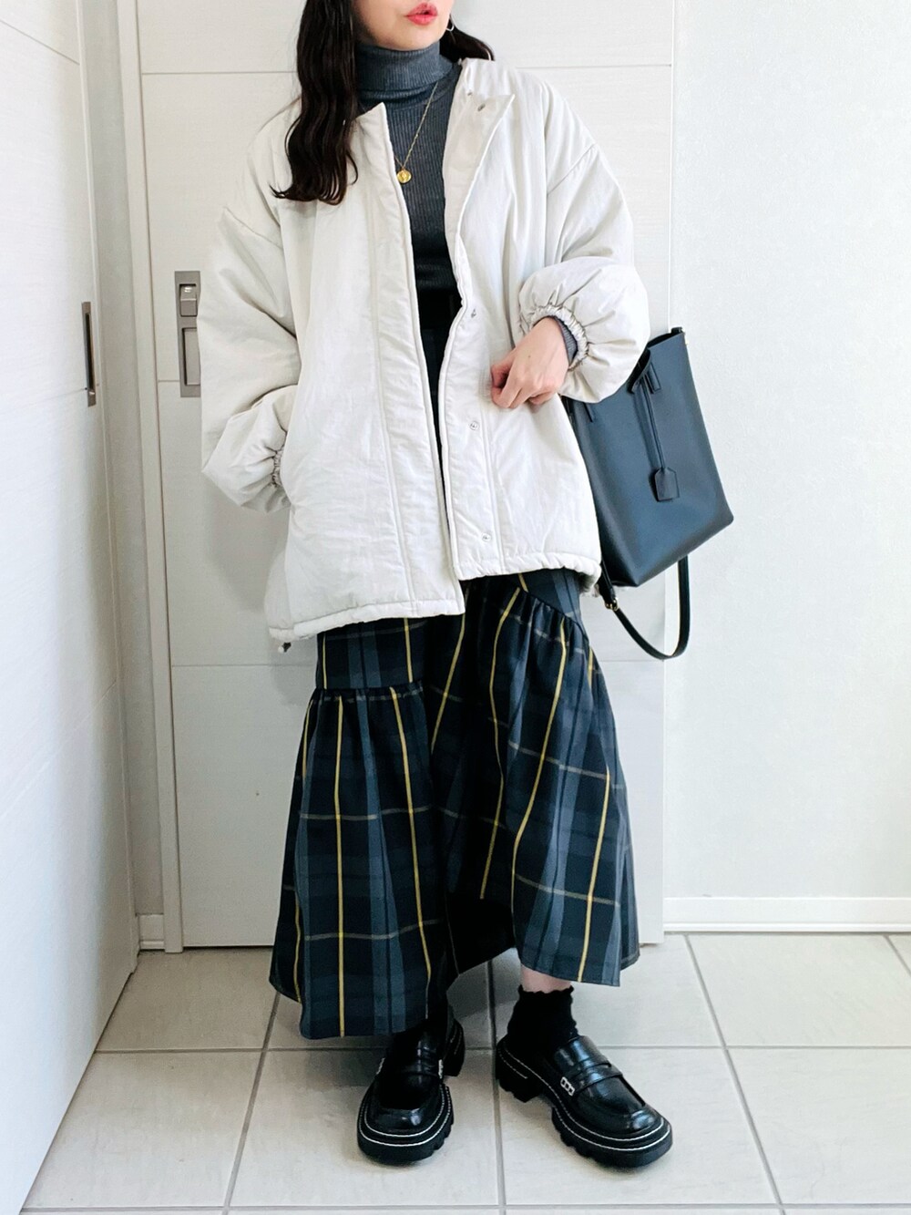ホワイト系のブルゾン、グレー系のニット/セーター、ブラック系のスカートを着用したレディースの秋コーディネートの5枚目の写真