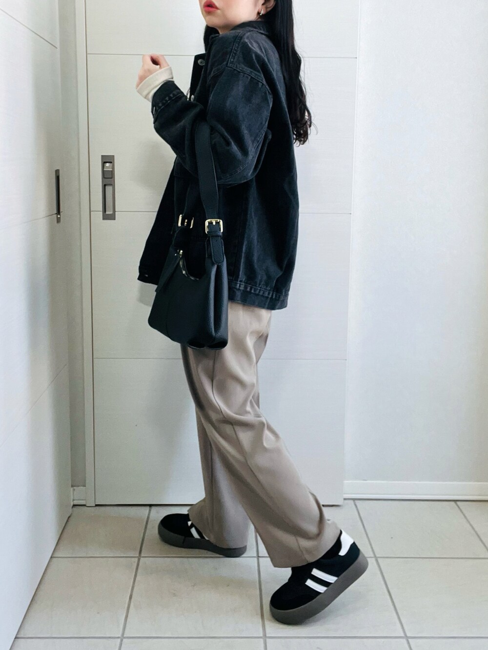 ブラック系のデニムジャケット、ブラック系のスニーカー、ブラック系のショルダーバッグを着用したレディースの冬コーディネートの5枚目の写真