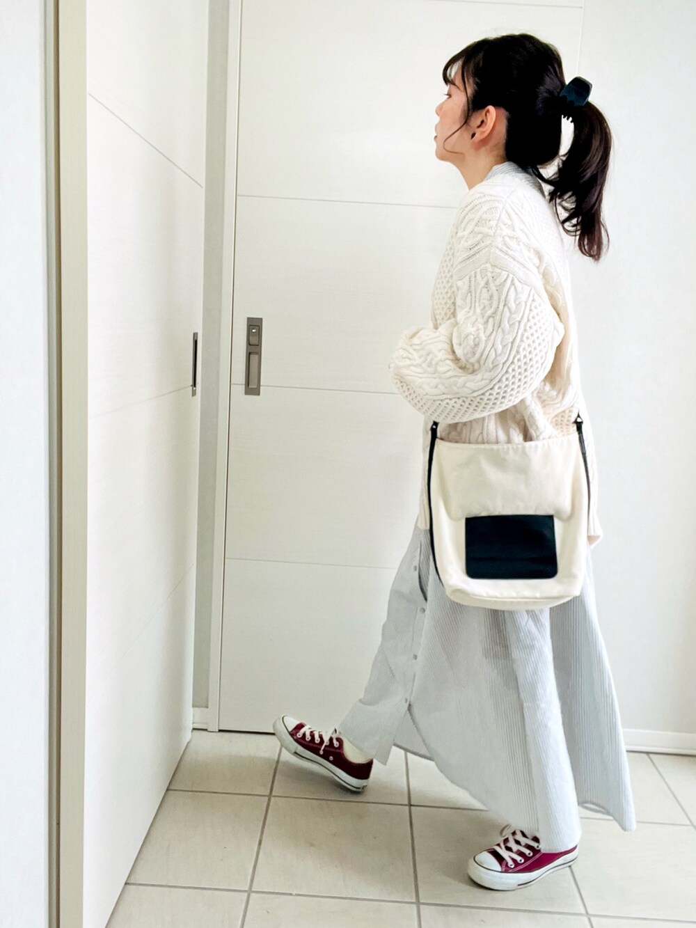 ブラック系のワンピース、ホワイト系のニット/セーター、レッド系のスニーカーを着用したレディースの冬コーディネートの5枚目の写真