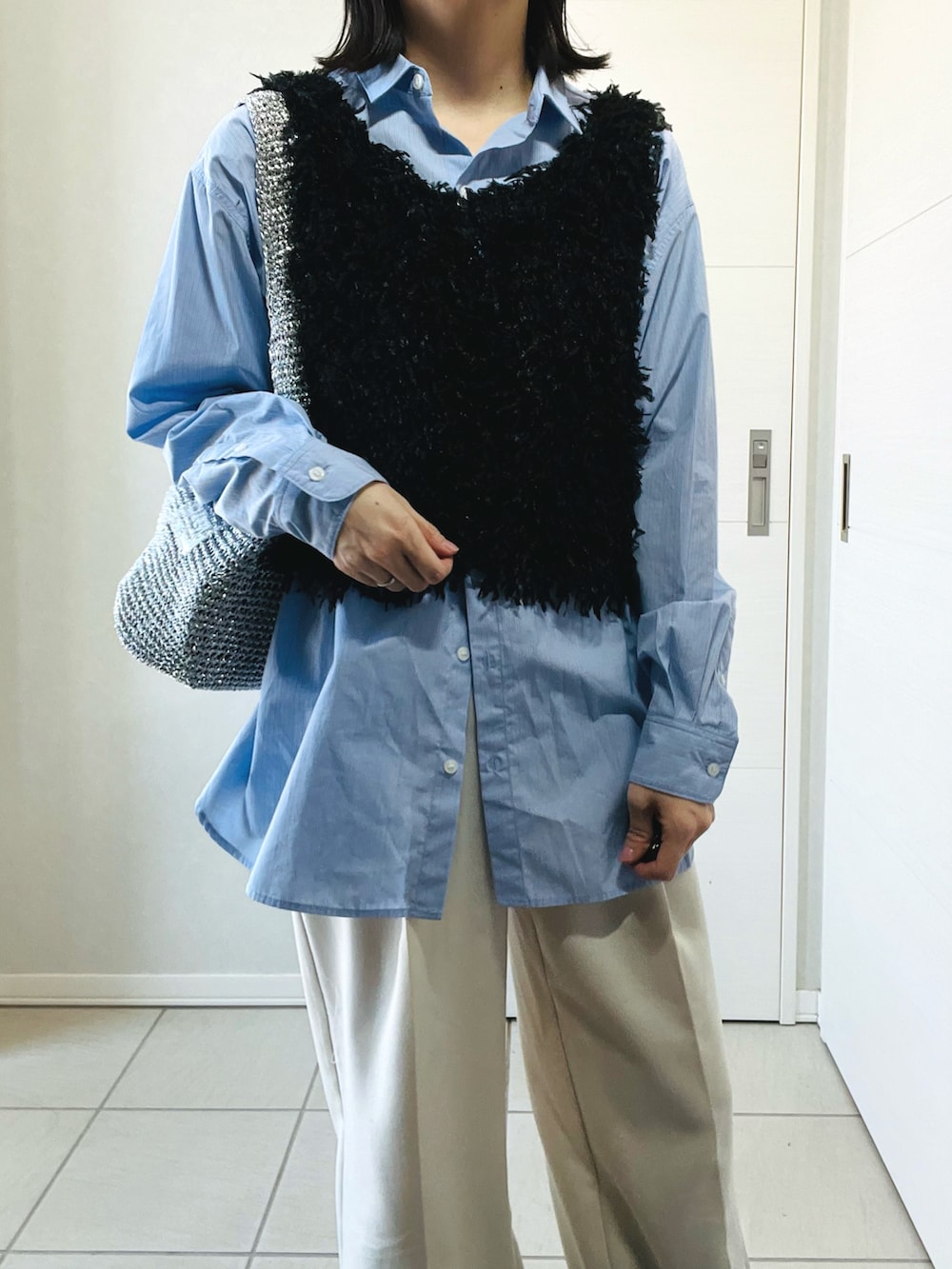 ブラック系のベスト、ブルー系のシャツ/ブラウス、ホワイト系のスラックスを着用したレディースの春コーディネートの2枚目の写真