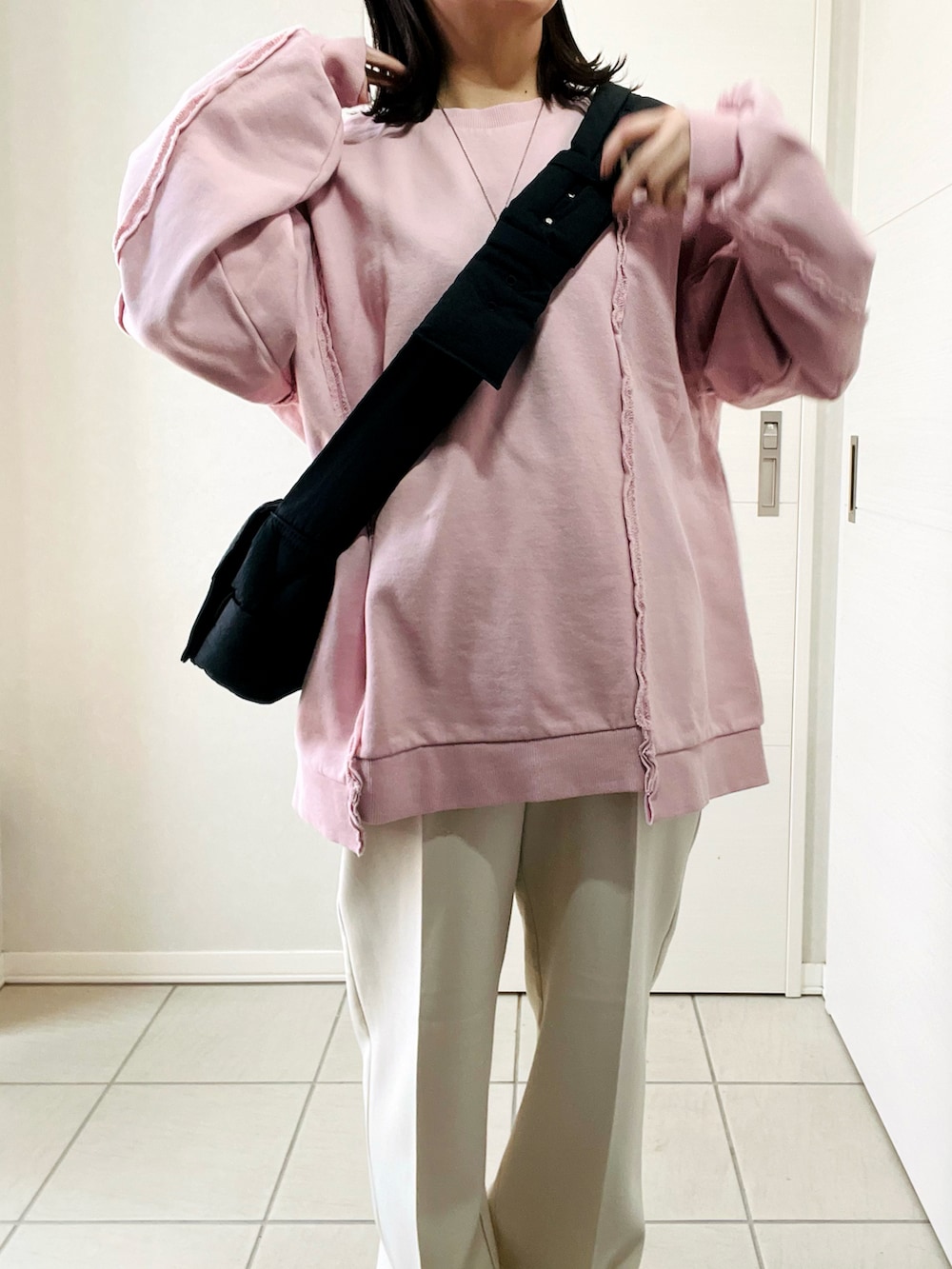 ピンク系のスウェット、ホワイト系のスラックス、ブラック系のスニーカーを着用したレディースの冬コーディネートの2枚目の写真