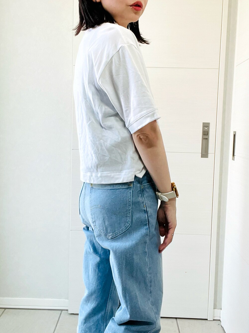 ホワイト系のポロシャツ、ブルー系のデニムパンツ、ホワイト系のスニーカーを着用したレディースの夏コーディネートの3枚目の写真