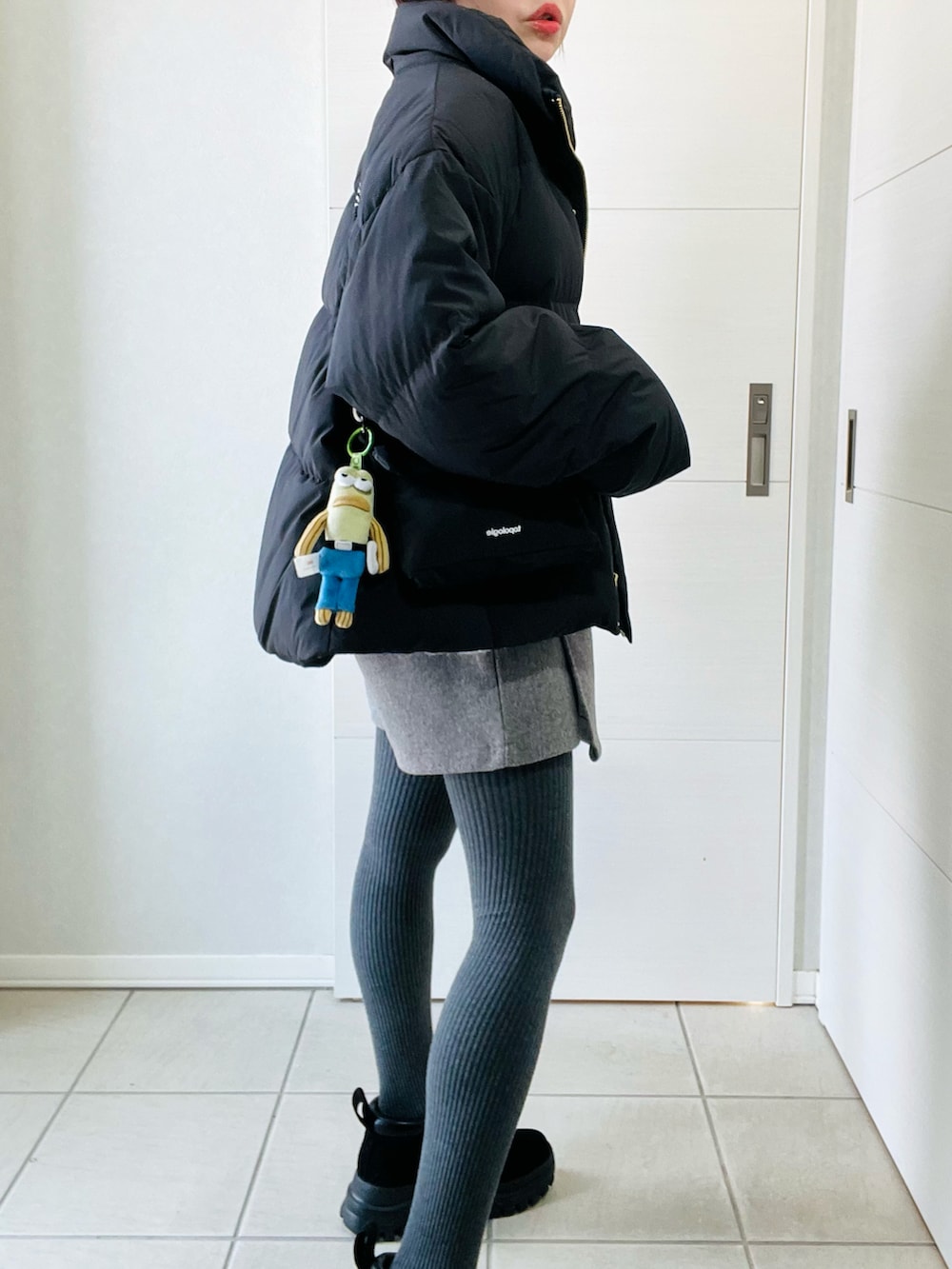 ブラック系のダウンジャケット/コート、ブラック系のブーツ、ホワイト系のカーディガン/ボレロを着用したレディースの春コーディネートの3枚目の写真