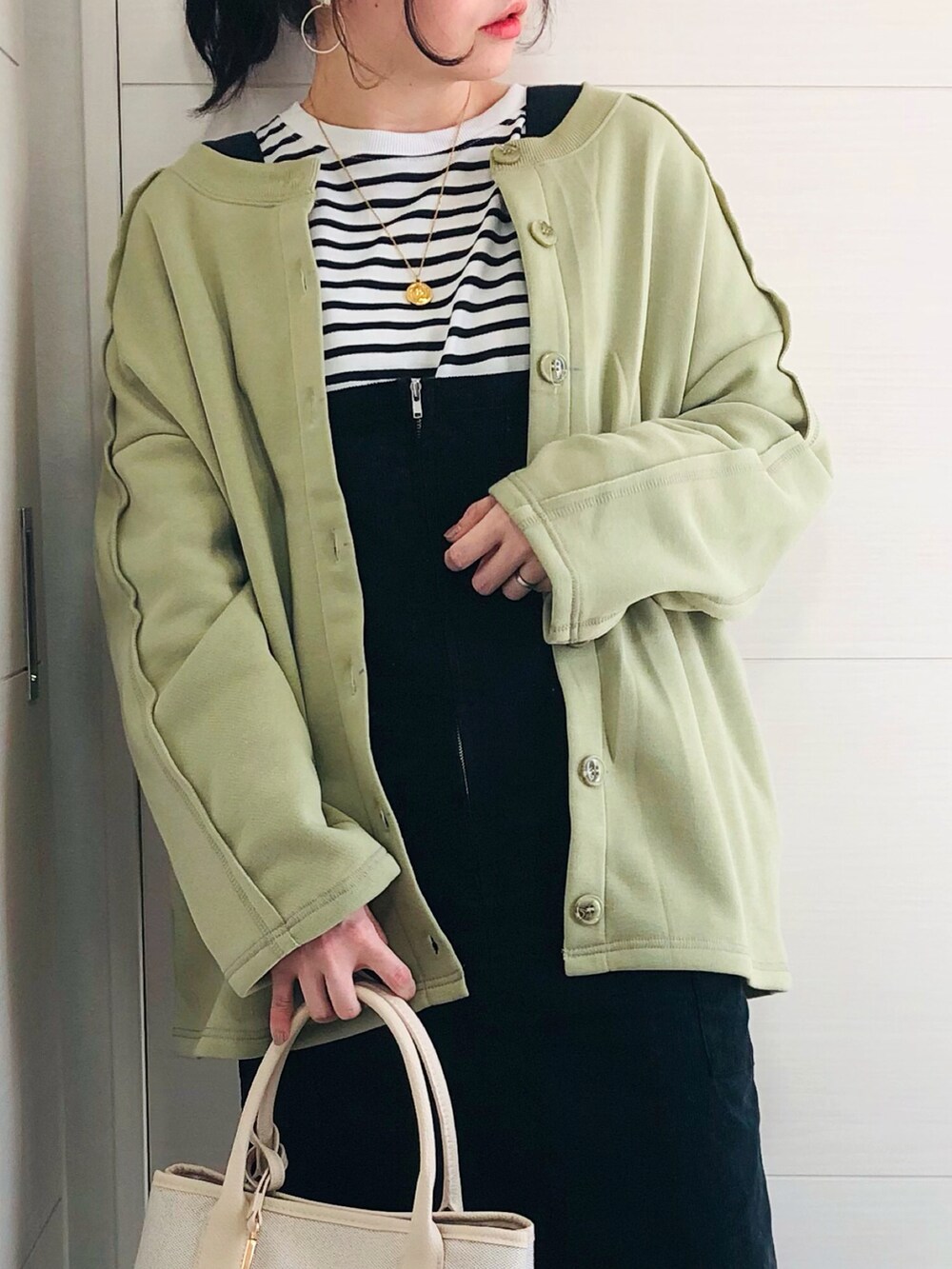 グリーン系のカーディガン/ボレロ、ブラック系のTシャツ/カットソー、ブラック系のジャンパースカートを着用したレディースの冬コーディネートの4枚目の写真