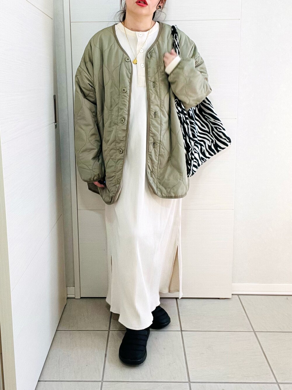 グリーン系のノーカラージャケット、ホワイト系のワンピース、ブラック系のスニーカーを着用したレディースの冬コーディネートの3枚目の写真