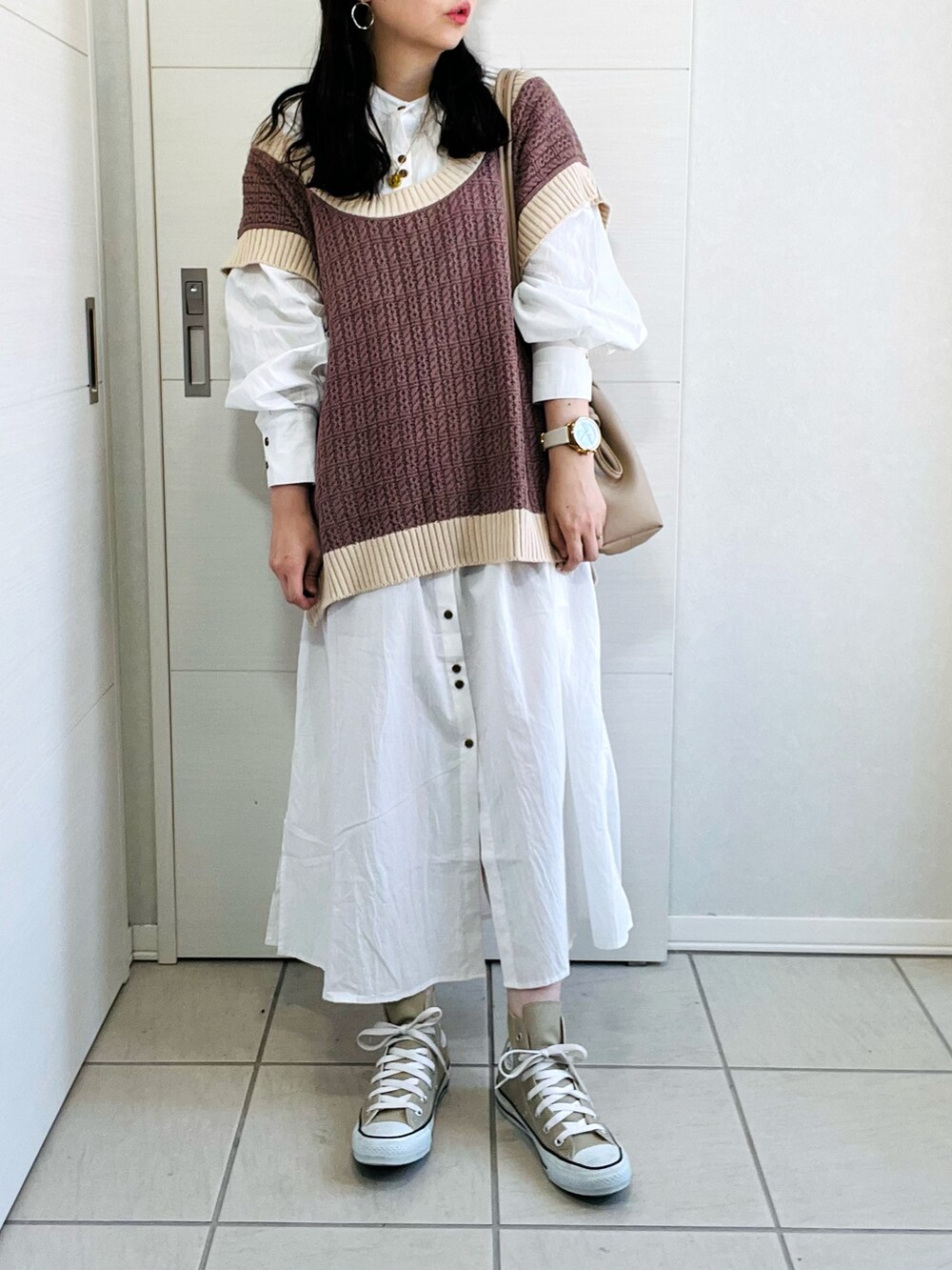 ブラウン系のベスト、ホワイト系のワンピース、ベージュ系のスニーカーを着用したレディースの秋コーディネートの2枚目の写真