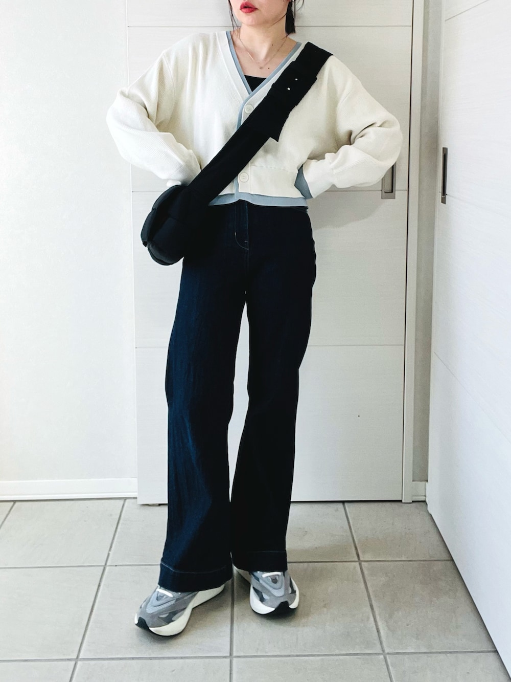 ホワイト系のカーディガン/ボレロ、グレー系のスニーカー、ブルー系のデニムパンツを着用したレディースの春コーディネートの4枚目の写真