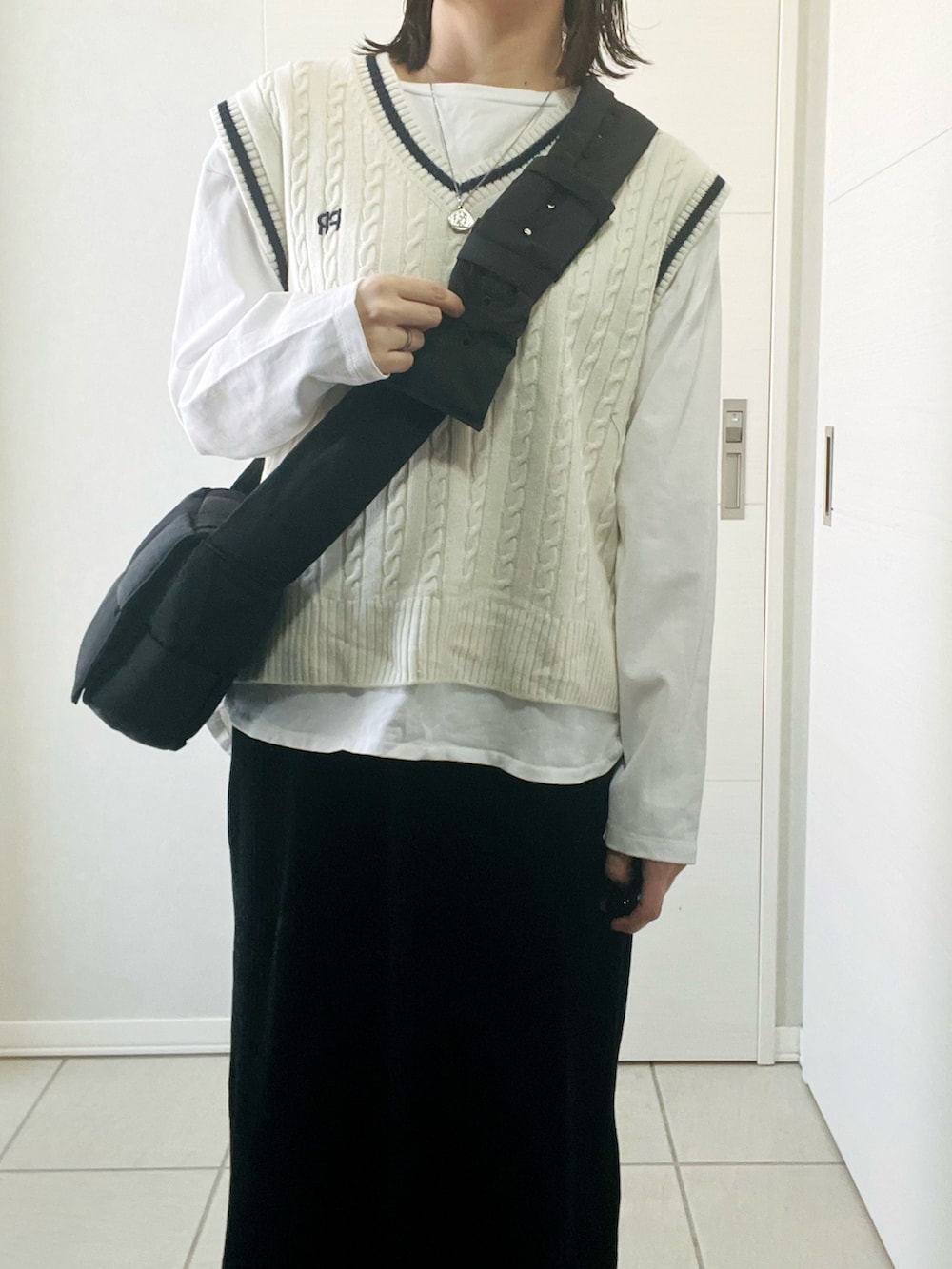 ホワイト系のTシャツ/カットソー、ホワイト系のベスト、ブラック系のスカートを着用したレディースの冬コーディネートの2枚目の写真