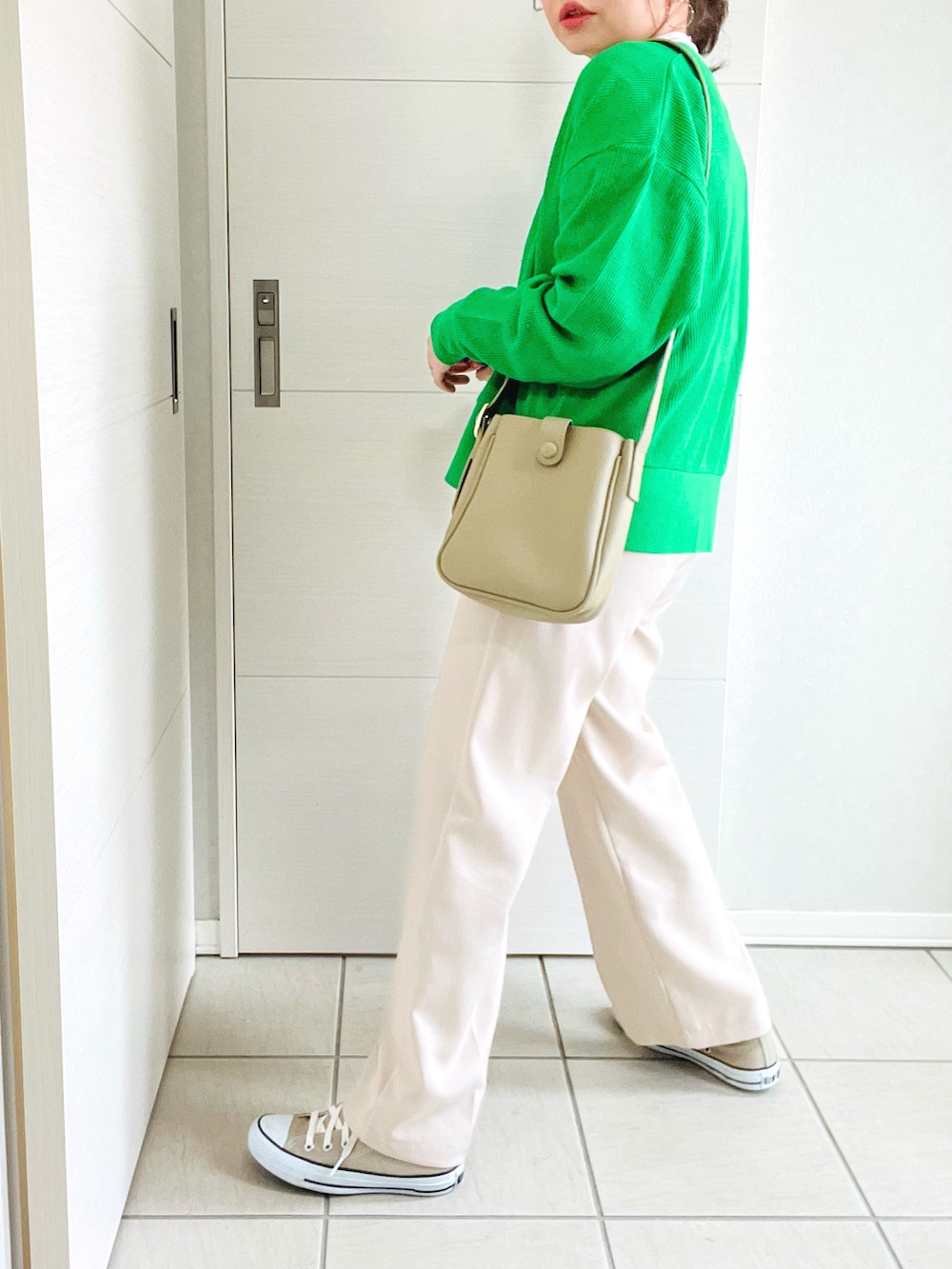 グリーン系のカーディガン/ボレロ、ベージュ系のTシャツ/カットソー、ホワイト系のスラックスを着用したレディースの春コーディネートの5枚目の写真
