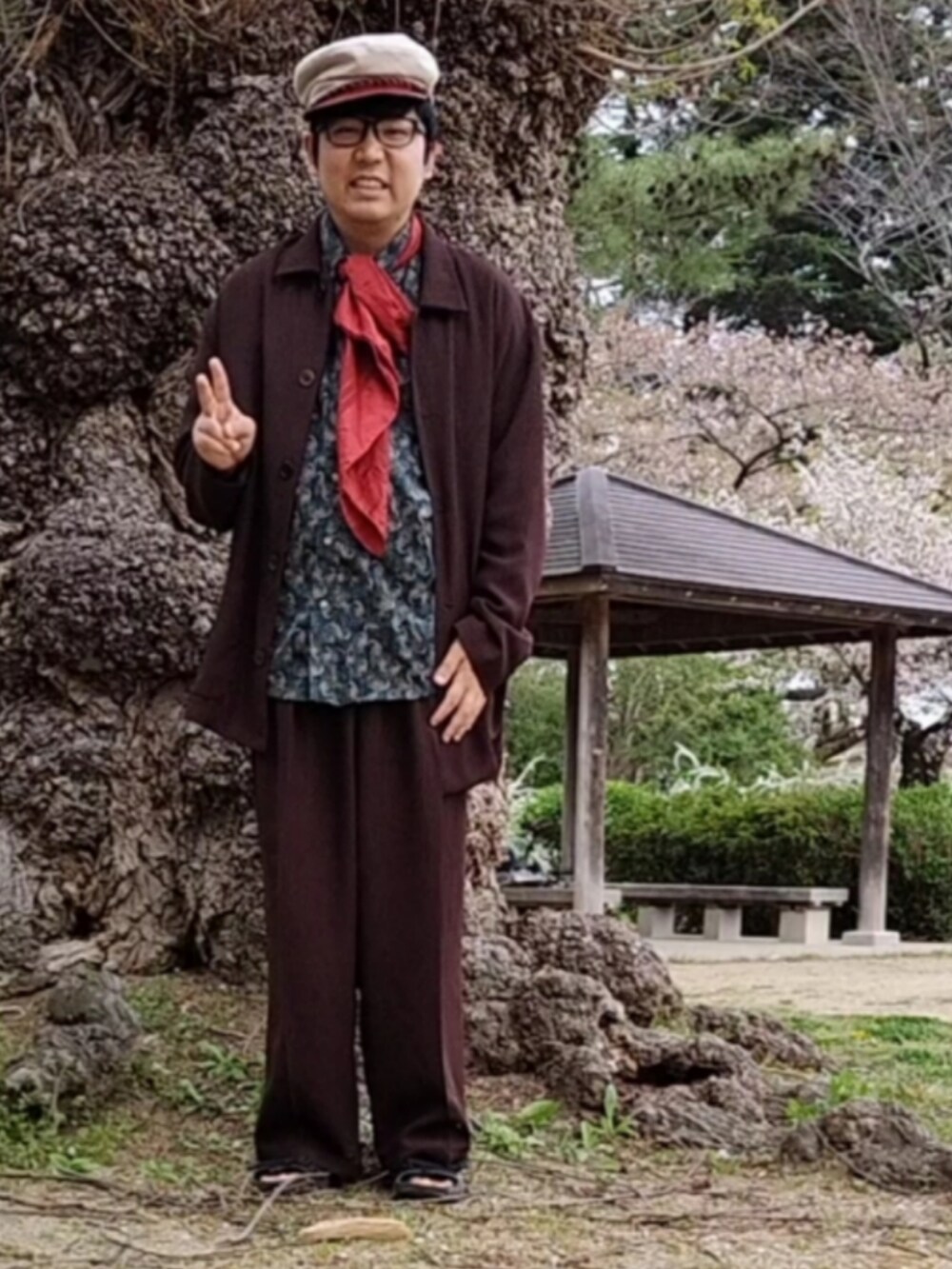 グリーン系のシャツ/ブラウス、ブラウン系のスラックス、レッド系のストール/ショールを着用したメンズの春コーディネートの2枚目の写真