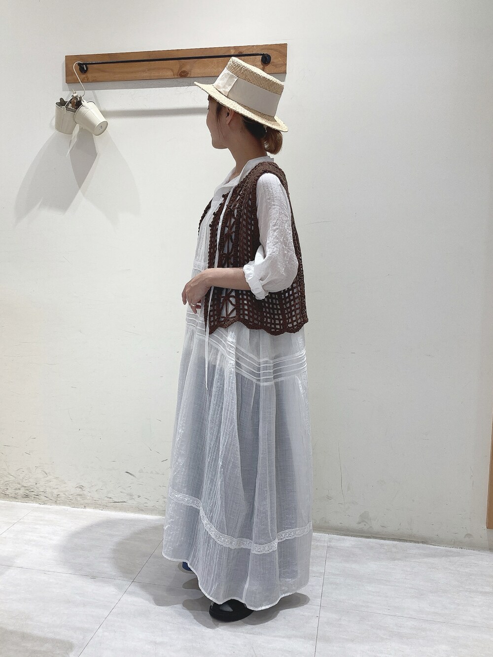 ブラウン系のベスト、ホワイト系のワンピース、ブルー系のその他パンツを着用したレディースの夏コーディネートの2枚目の写真