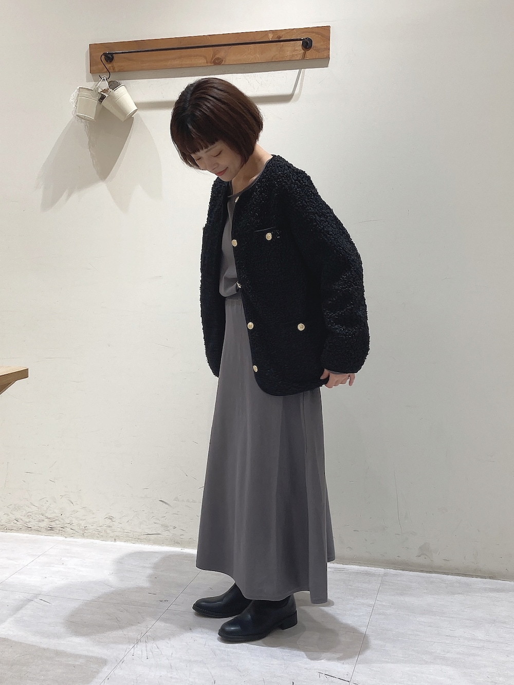 グレー系のニット/セーター、グレー系のスカート、ブラック系のノーカラージャケットを着用したレディースの秋コーディネートの2枚目の写真