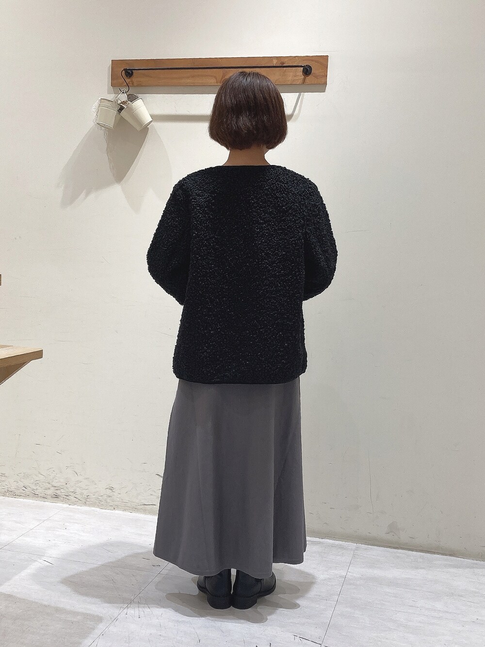 グレー系のニット/セーター、グレー系のスカート、ブラック系のノーカラージャケットを着用したレディースの秋コーディネートの3枚目の写真